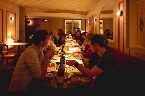 Vue sur la longue table du dîner d’Espèces d’espaces dans la salle du Daimant St-Honoré, avec des convives de dos et de profil.