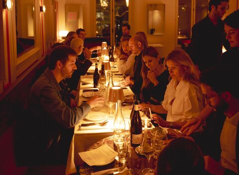 Les invités du dîner d’Espèces d’espaces attablés dans la lumière chaude du restaurant Daimant St-Honoré, avec des bouteilles de vin sur la table.